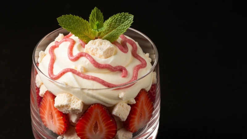 Eton mess dessert with crushed meringue whipped cream and fresh strawberries in a glass